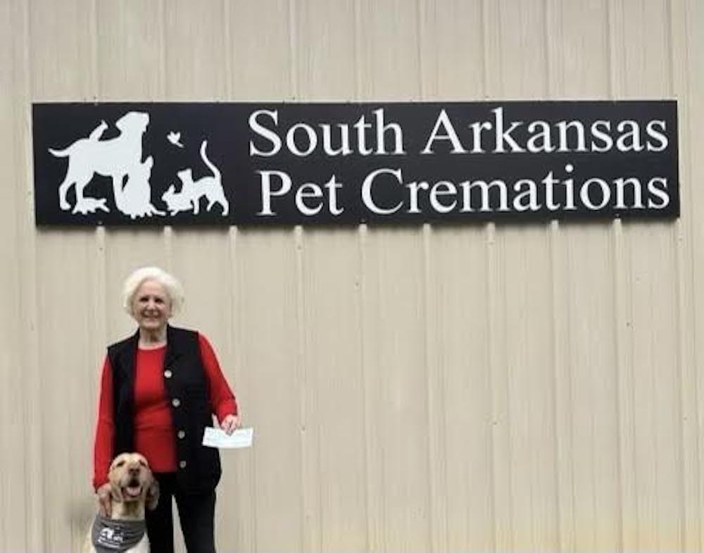 A woman standing in front of a sign that says " south arkansas pet cremation ".