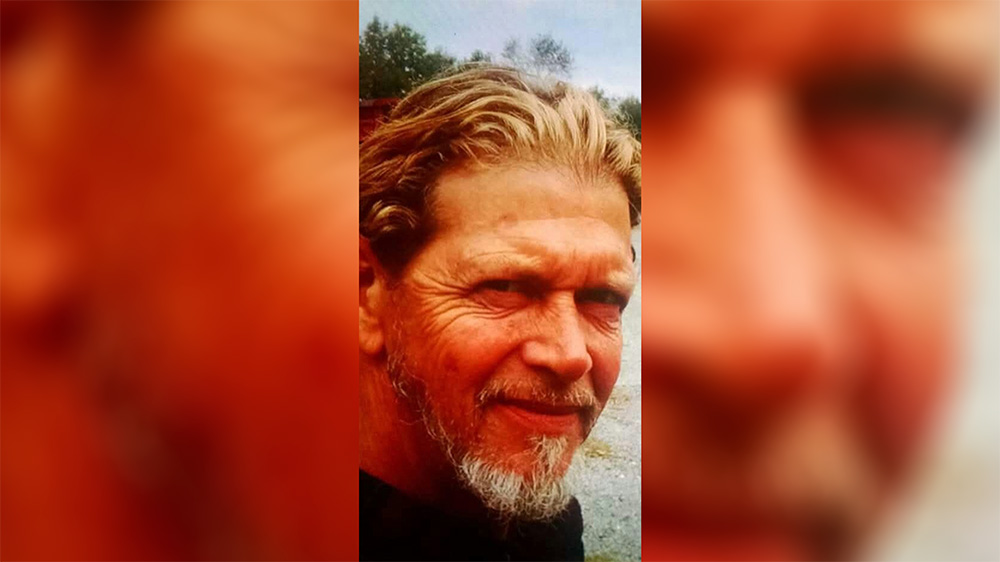 A man with long hair and beard smiling for the camera.