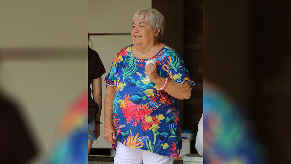 A woman in blue shirt holding a wii controller.
