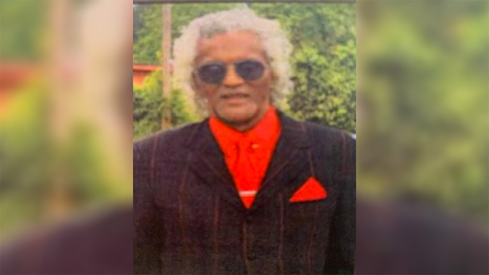 A man with white hair and sunglasses in a suit.