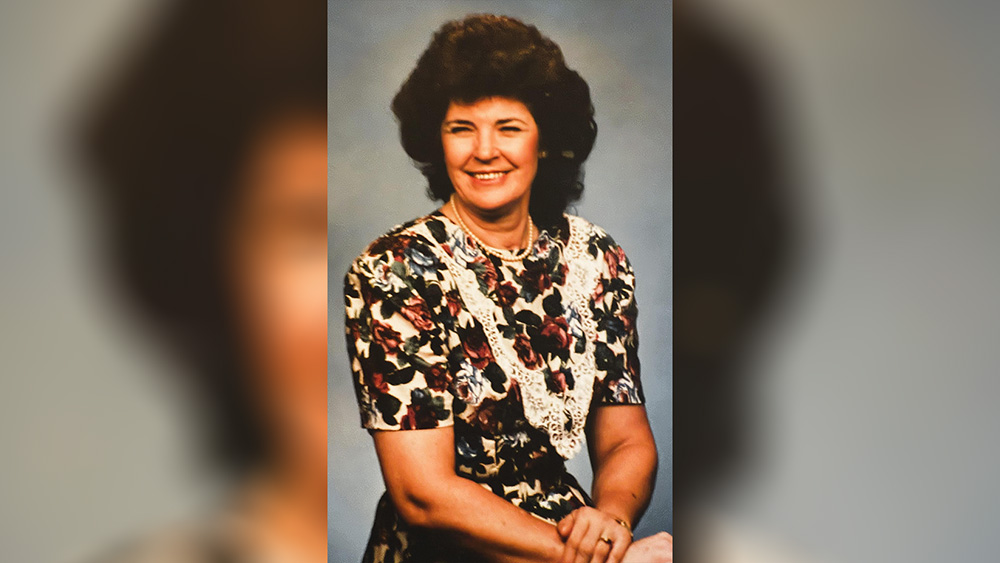 A woman in floral print shirt and black skirt.
