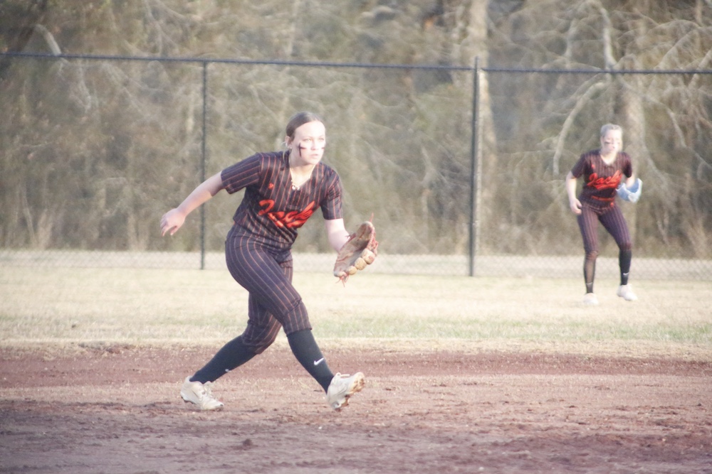 A woman in black shirt throwing a ball.