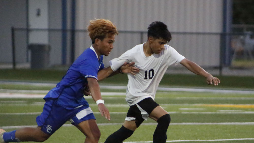 Two men playing soccer on a field.