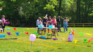 A group of people standing around a table in the grass.