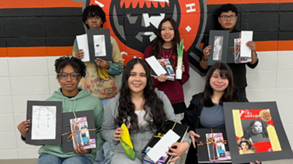 A group of people holding up books in front of a wall.