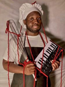 A man in chef 's hat holding a keyboard.