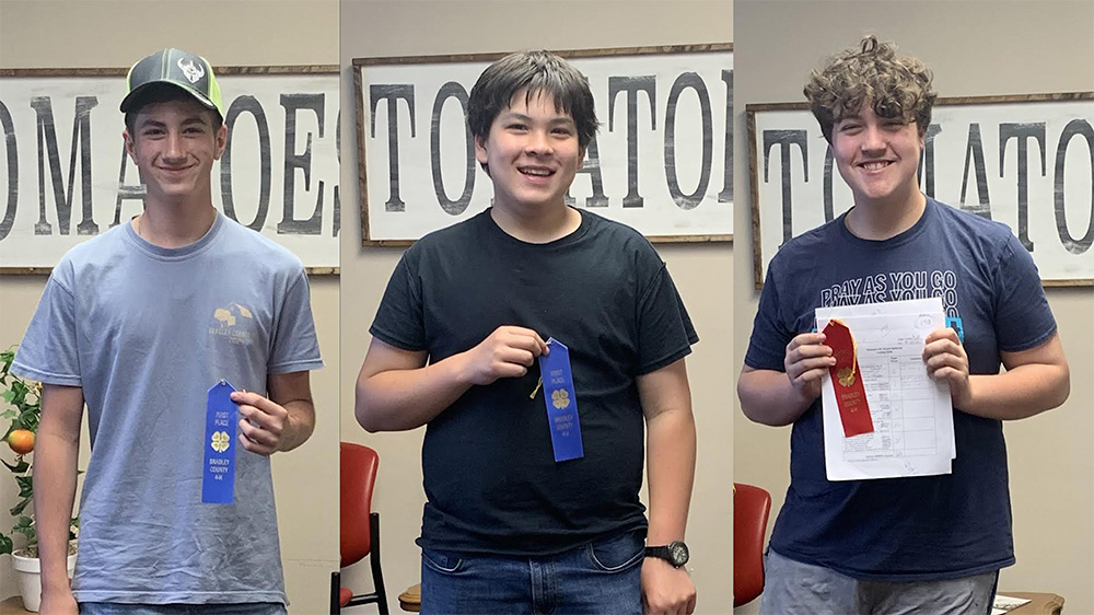 Three men holding ribbons in a room with chairs.