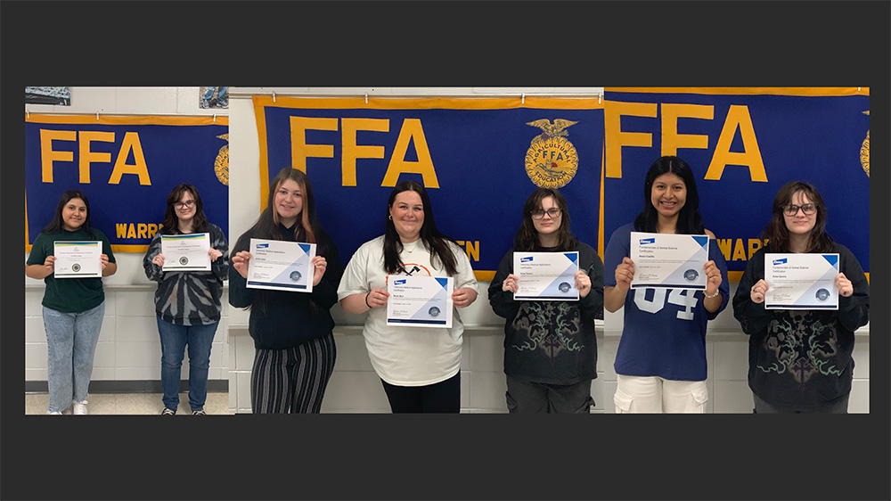 Five women holding up certificates in front of a ffa banner.
