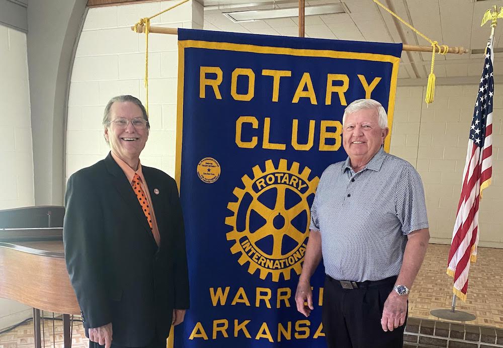 Two men standing next to each other in front of a banner.