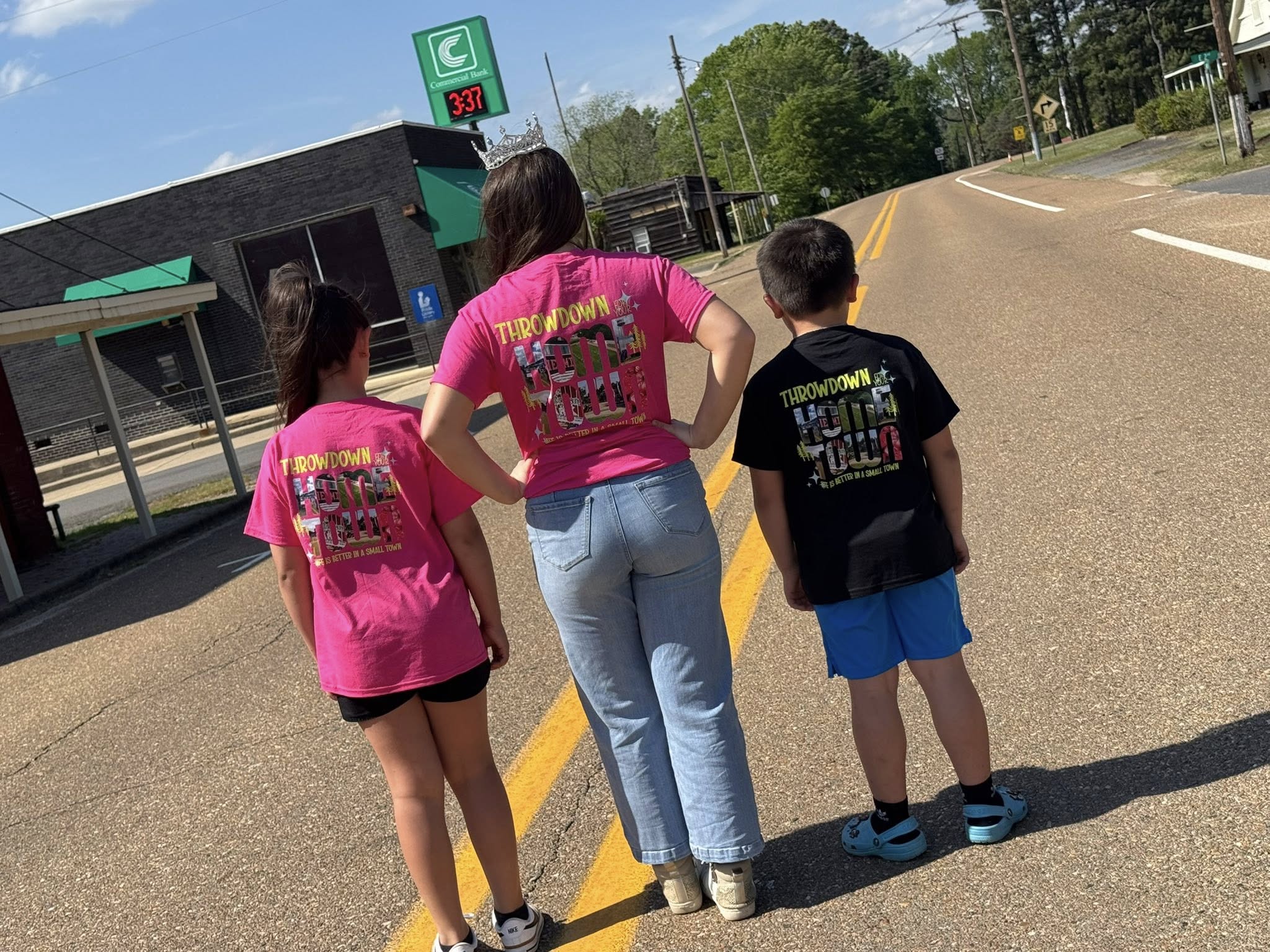 Three children standing on the side of a road.
