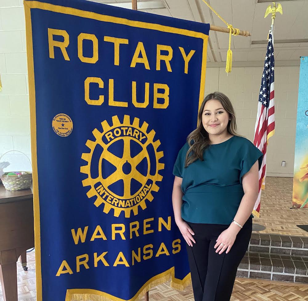 A woman standing in front of a blue banner.