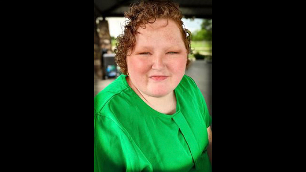 A woman in green shirt smiling for the camera.