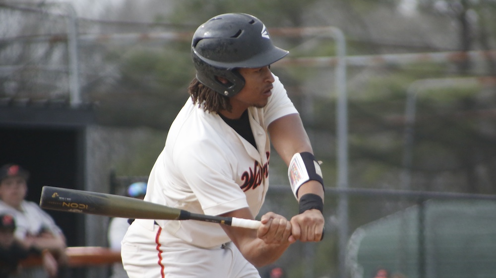 A baseball player swinging at the ball with his bat.