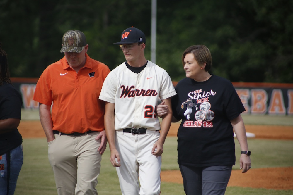 A man and two women walking on the field