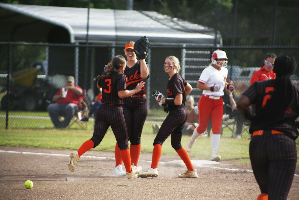 A group of girls playing softball on the field.