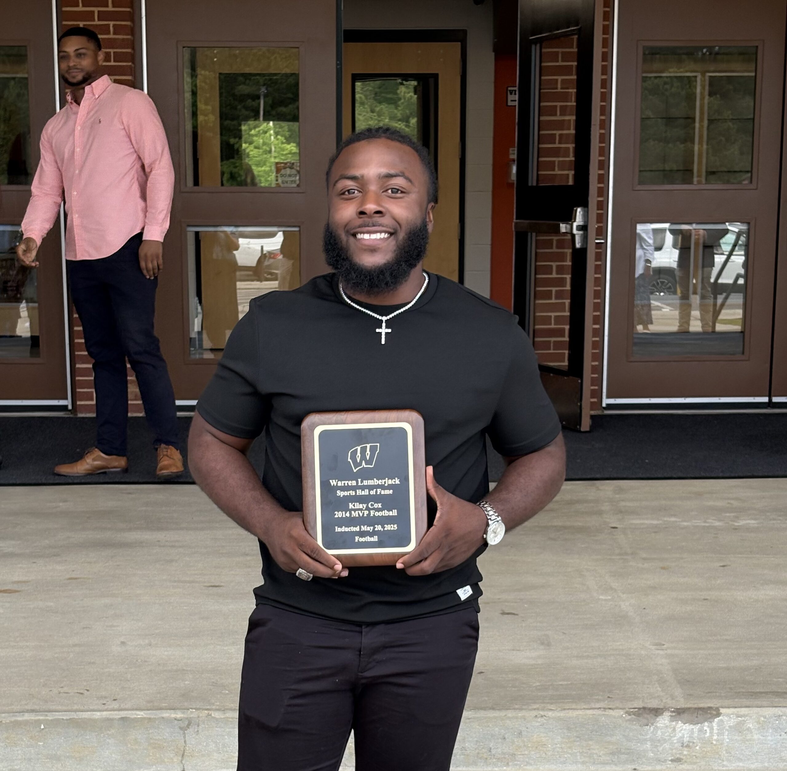 A man holding up a plaque in front of some doors.