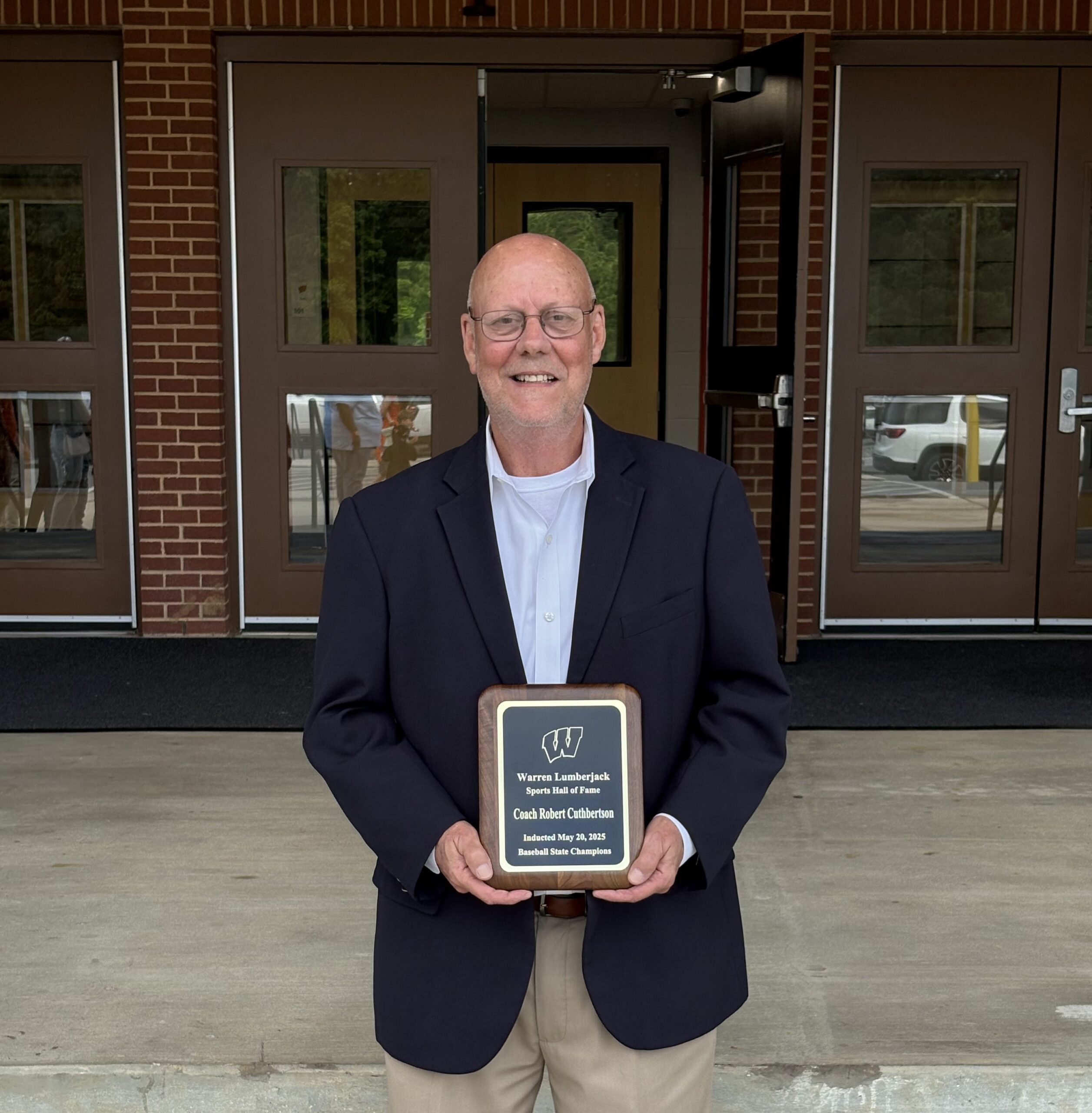 A man holding a plaque in front of two doors.