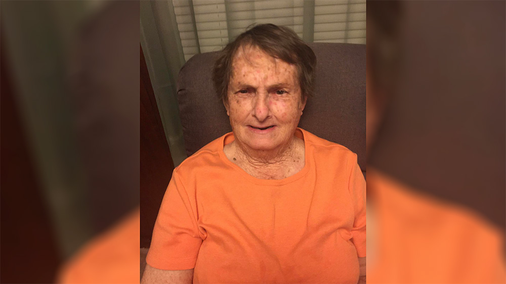 A woman in an orange shirt sitting on a chair.