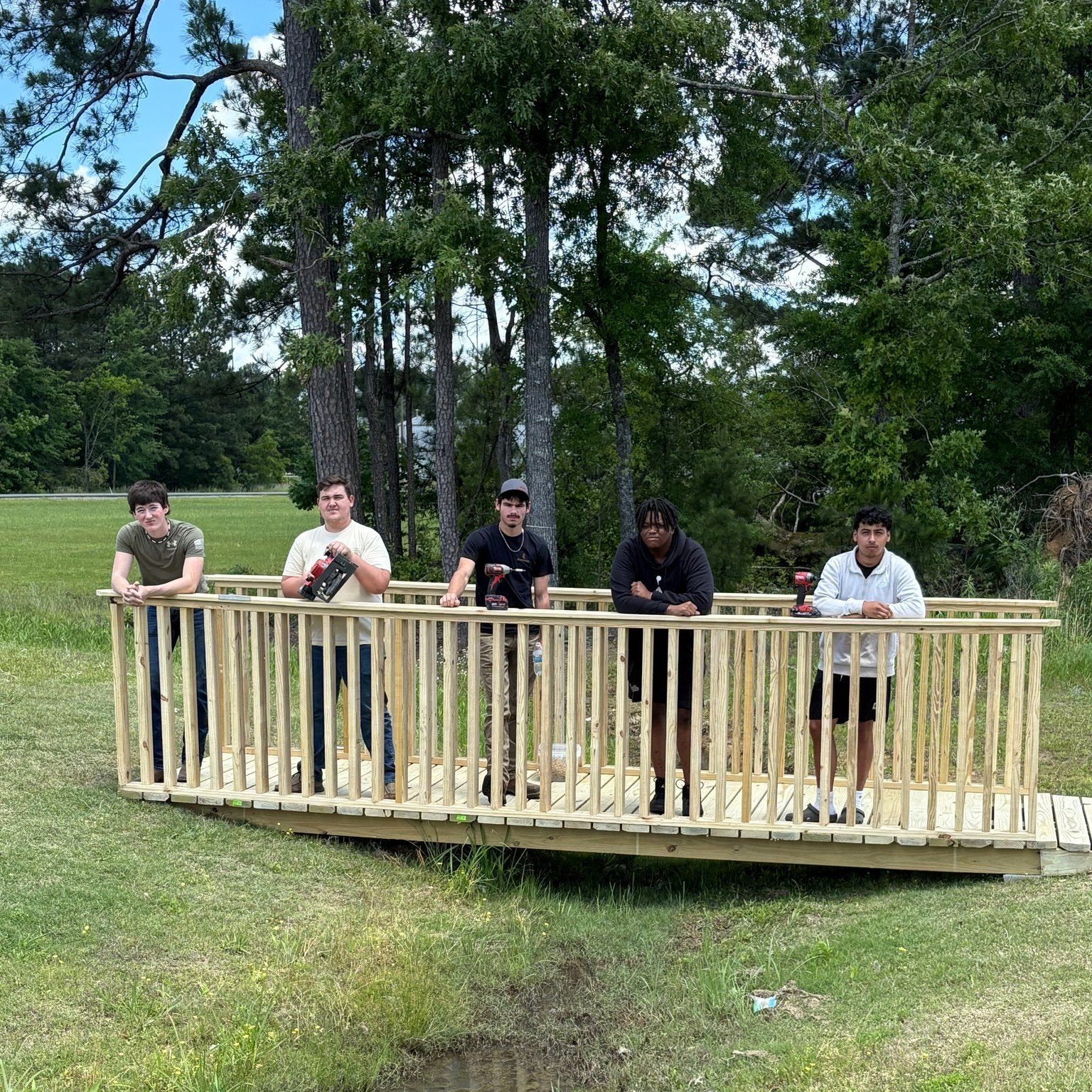 A group of people standing on top of a wooden bridge.